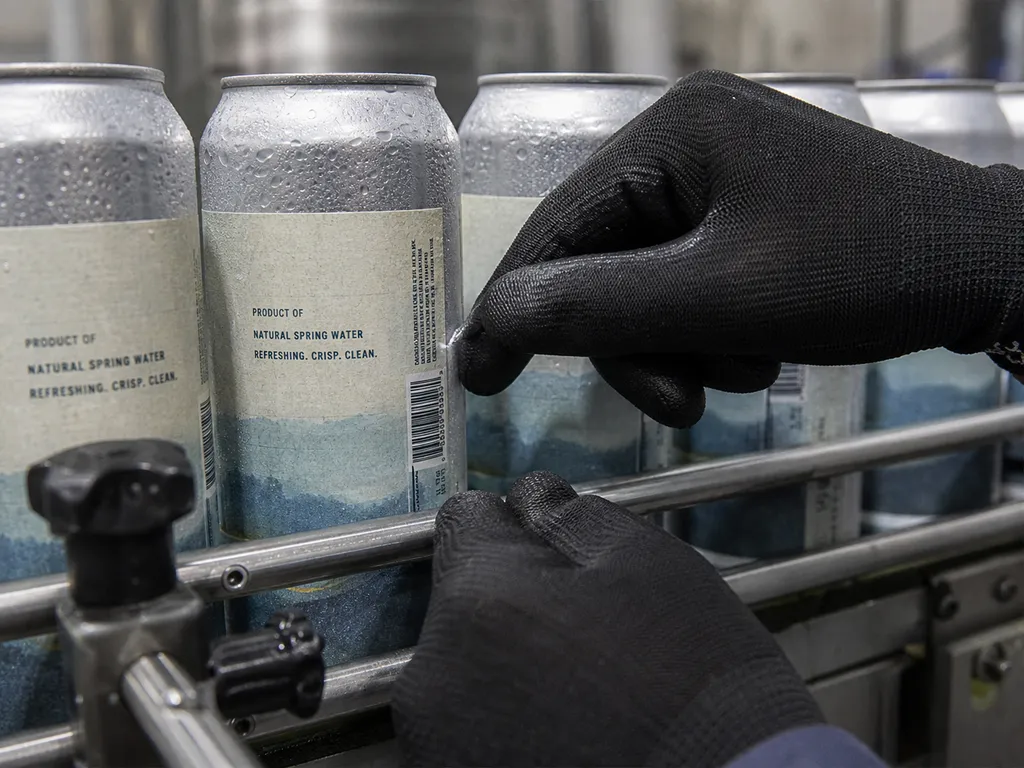 Chilled labeled cans moving through a packaging conveyor.